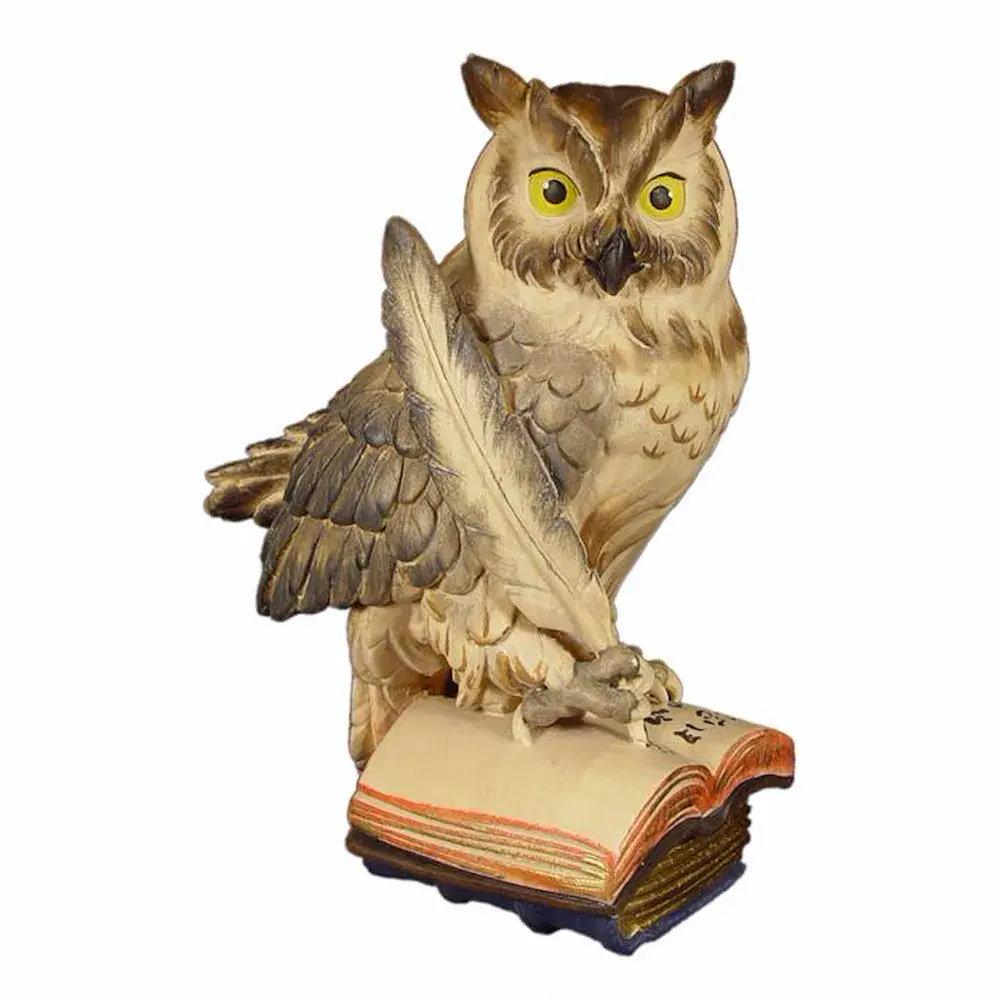 Búho sobre libros con pluma