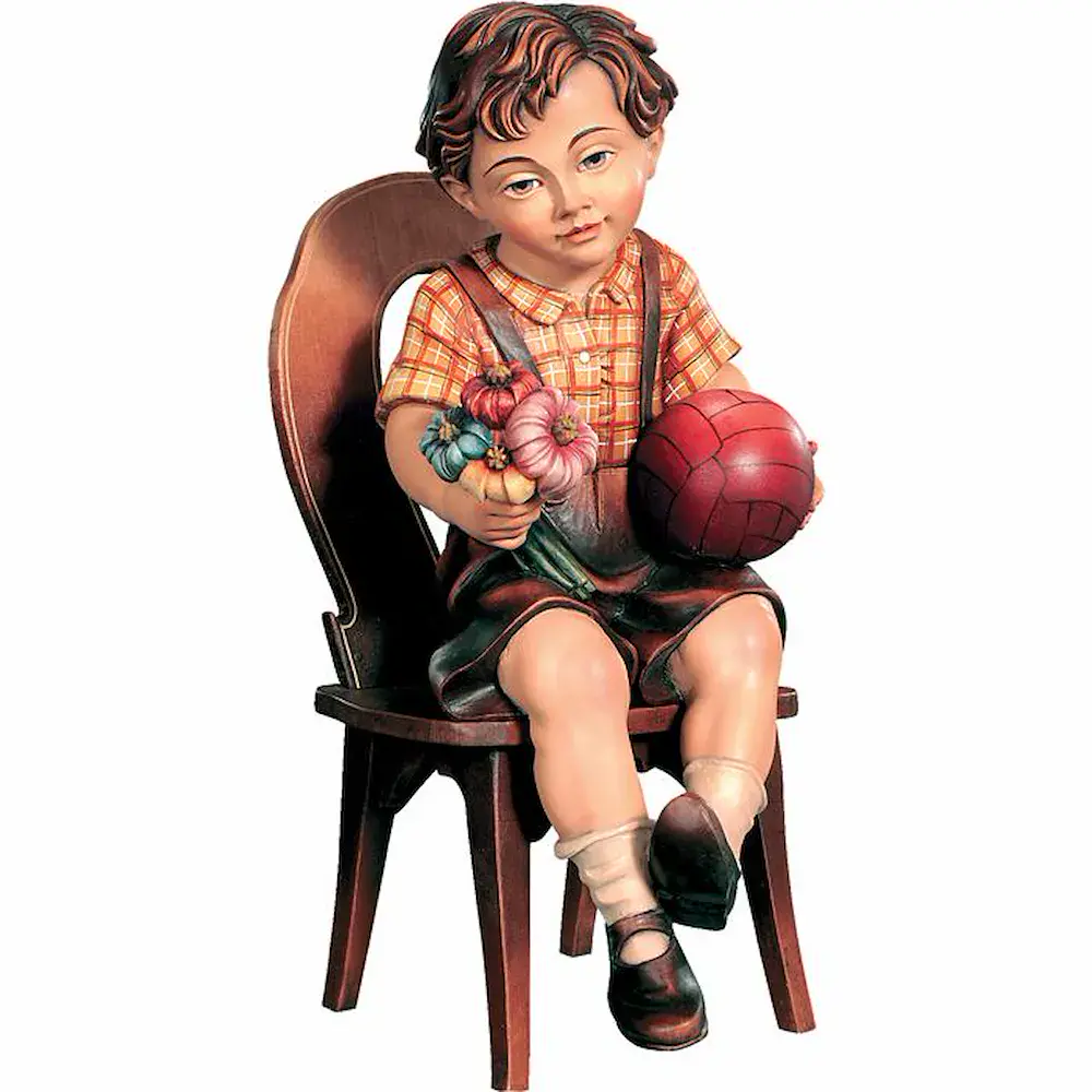 Niño sentado en una silla con balón y flores